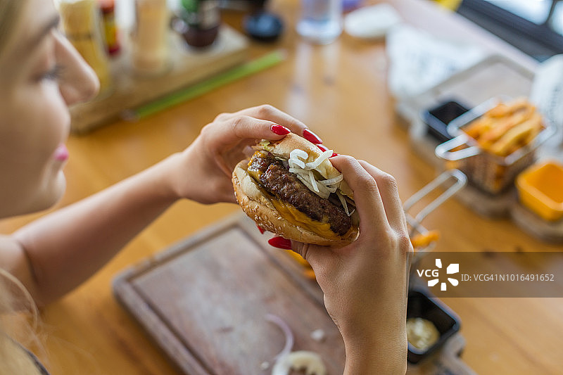 年轻女人在餐厅吃汉堡图片素材