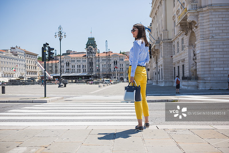 在街上通勤上班使用手机的年轻意大利女性图片素材