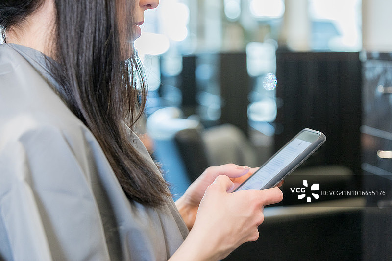 女人在美发沙龙使用智能手机图片素材