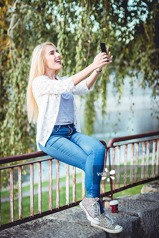 在栏杆上自拍的金发女子图片素材