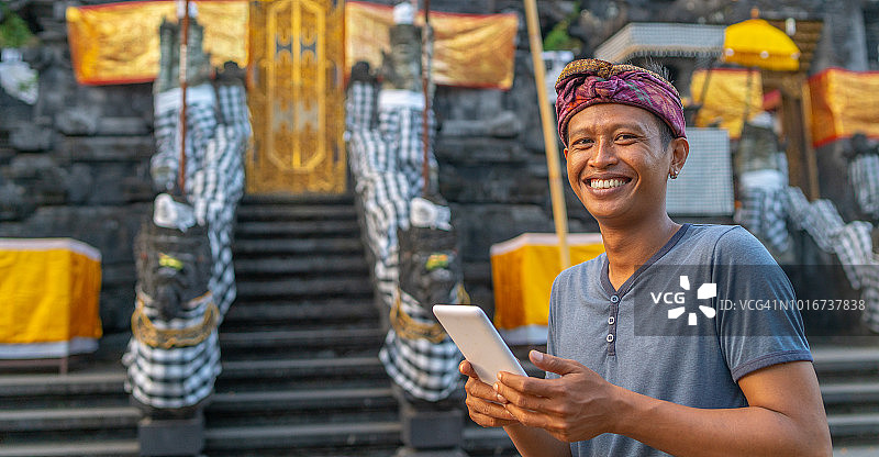 在巴厘岛寺庙使用平板电脑的年轻男子肖像图片素材