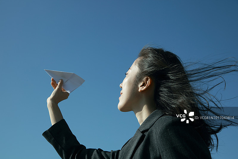 女商人拿着纸飞机朝向天空图片素材