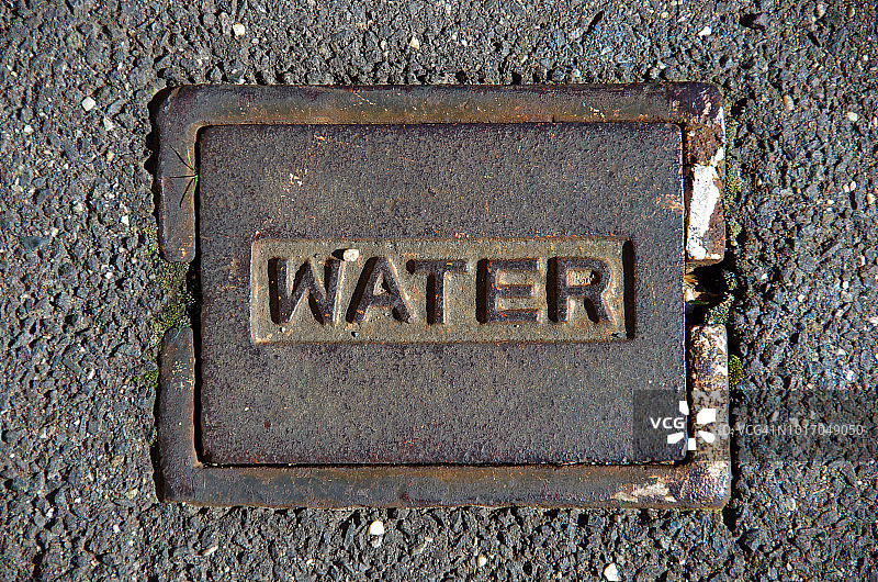 沥青人行道上的水表箱盖图片素材