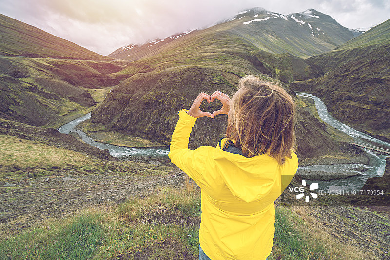 年轻女人在峡谷中用手指比心图片素材