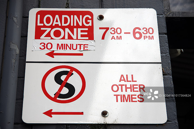 建筑物外立面的“30分钟装货区：上午7:30-下午6:30”和“其他时间禁止停车”标志图片素材