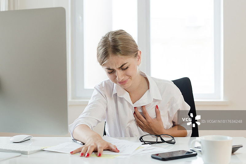 年轻女商人抚摸着她的胸口图片素材