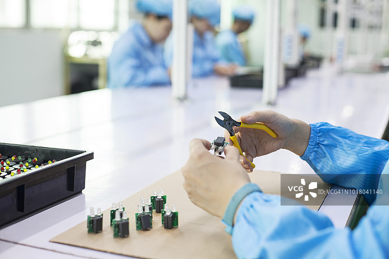 中国东莞LED打火机厂的工人拿着二极管图片素材