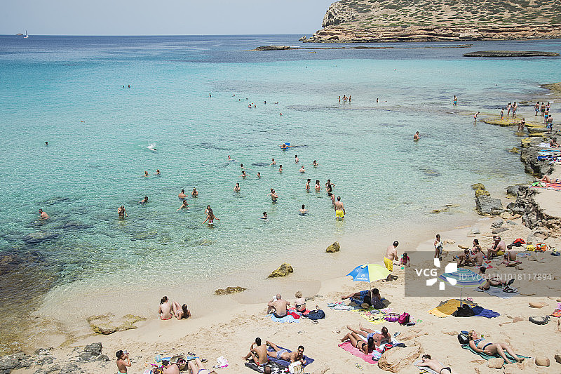 许多人在伊维萨岛的卡拉孔特游泳和日光浴。图片素材