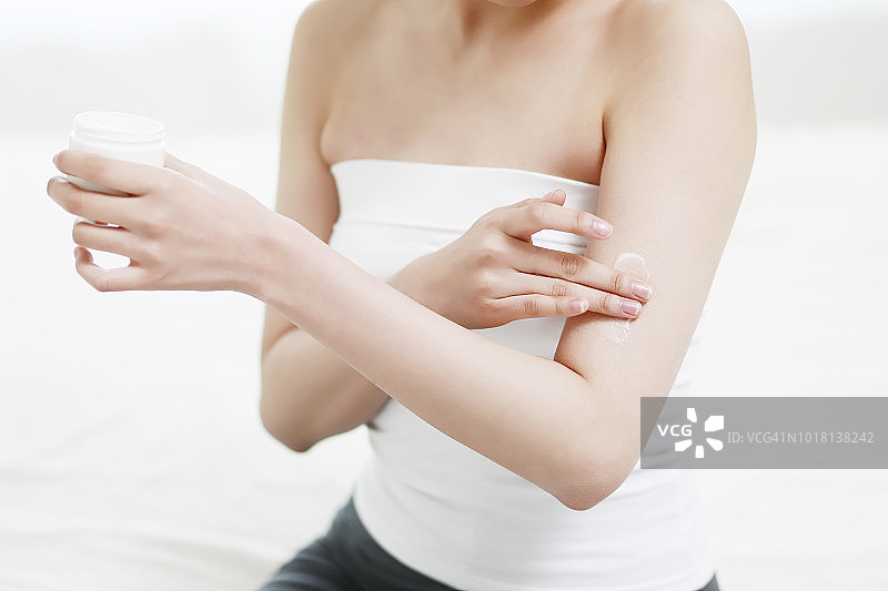年轻女人往手臂上涂身体乳图片素材
