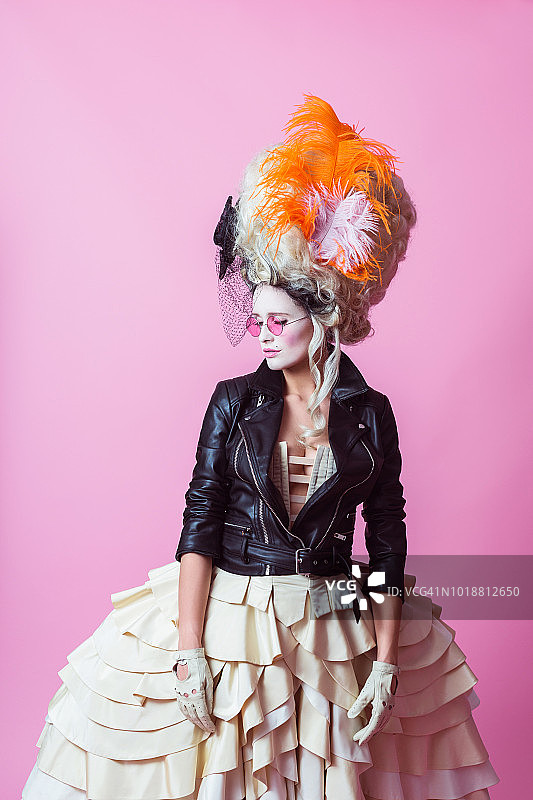 戴巴洛克假发和皮夹克的现代女性肖像，粉色背景图片素材