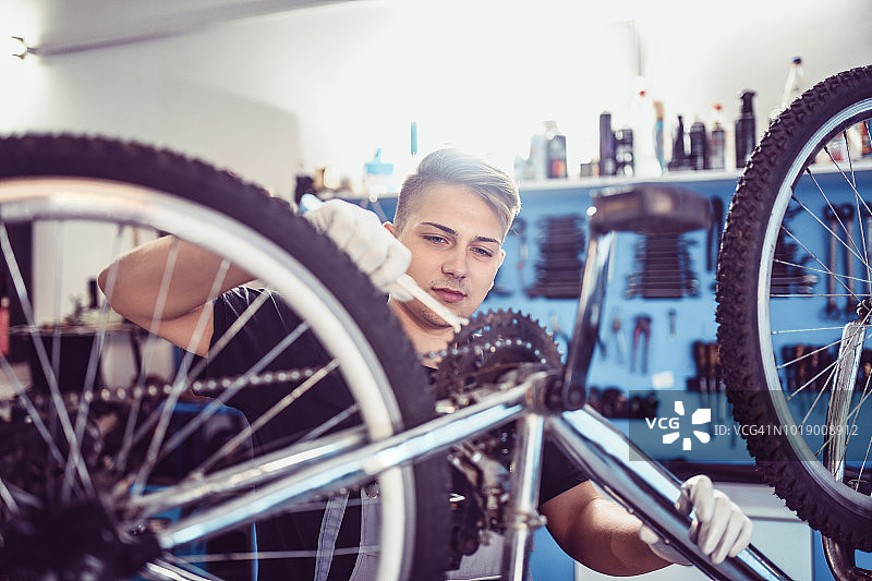 年轻学徒在工作室学习如何调整自行车齿轮图片素材