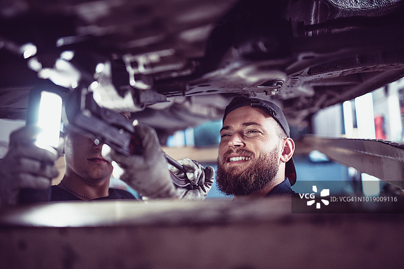汽车修理工和学徒修理故障车辆图片素材