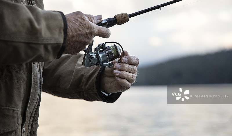 活跃的老年男人在山 Lake 湖钓鳟鱼图片素材