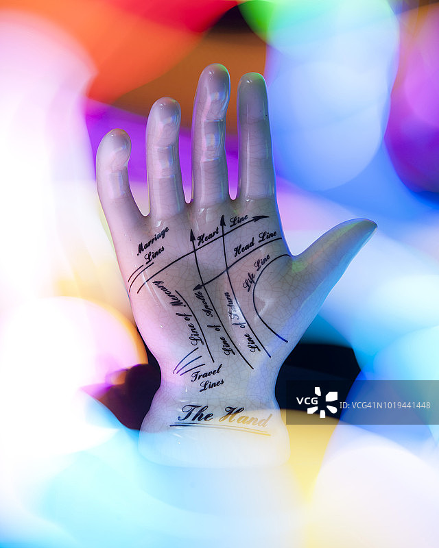 手绘手相纹路的陶瓷手，周围环绕着彩色灯光图片素材
