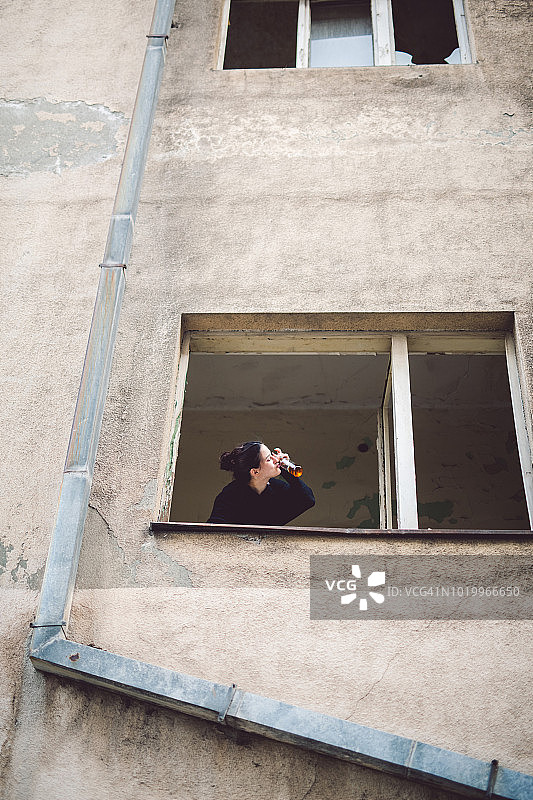 在破窗户旁的年轻女孩图片素材