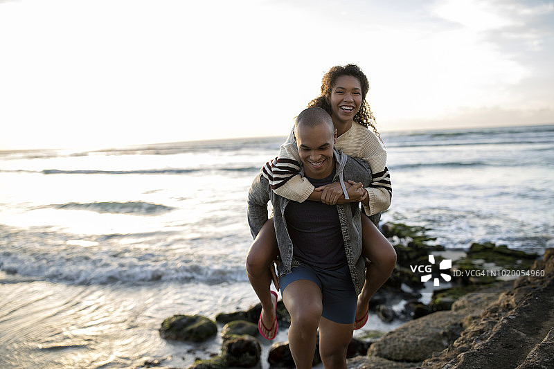 快乐的年轻人在海边背着女朋友图片素材