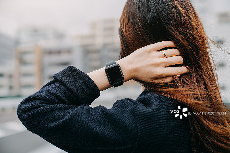 戴智能手表享受城市微风的女人图片素材