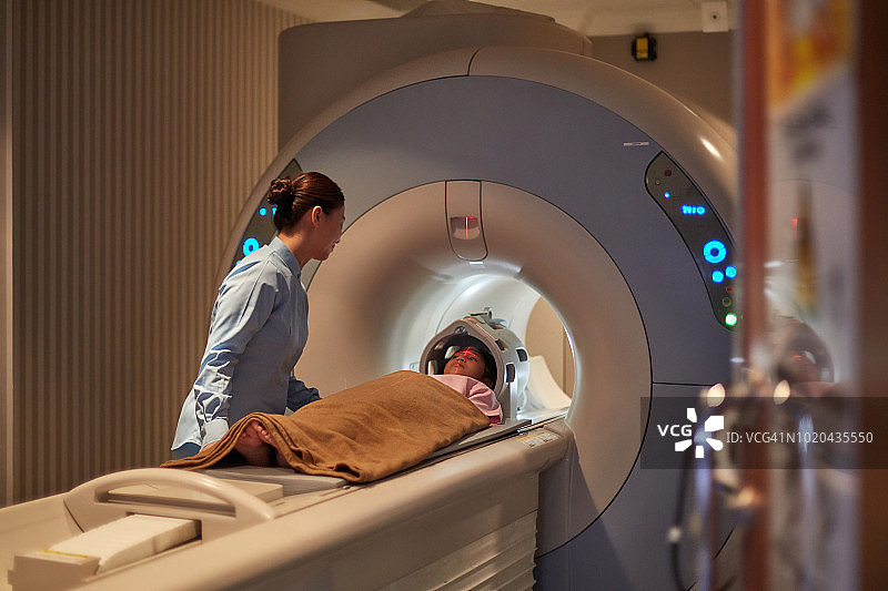 护士观察女孩的CT扫描图片素材