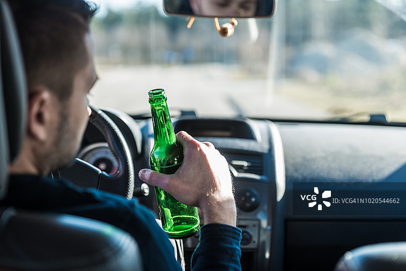 男人开车时喝啤酒图片素材