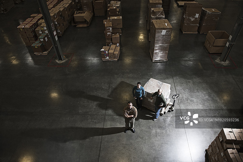 站在配送仓库中央的三个仓库工人图片素材