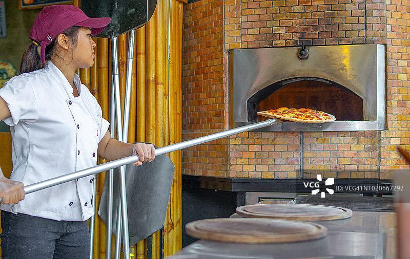 厨师将披萨放入砖炉中图片素材
