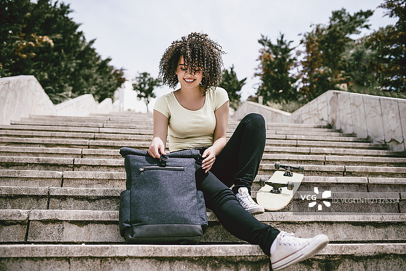 在楼梯上休息的可爱滑板女人图片素材