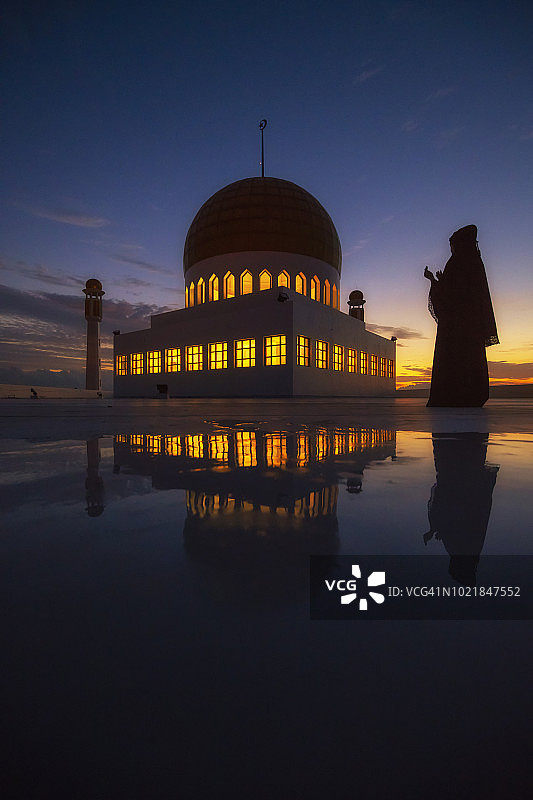 穆斯林祈祷，清真寺在前景中，日落景象图片素材