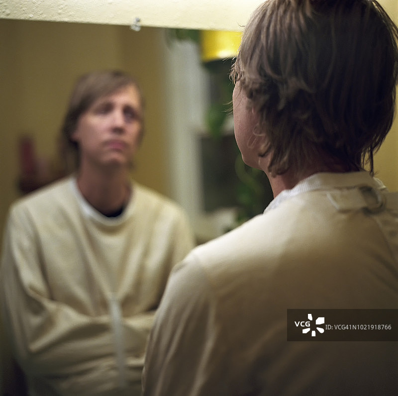 穿着束缚衣的男人在浴室镜子前凝视自己图片素材