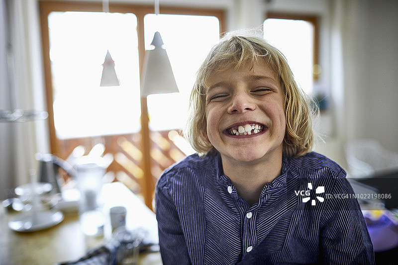 露出牙齿微笑的金发男孩肖像图片素材