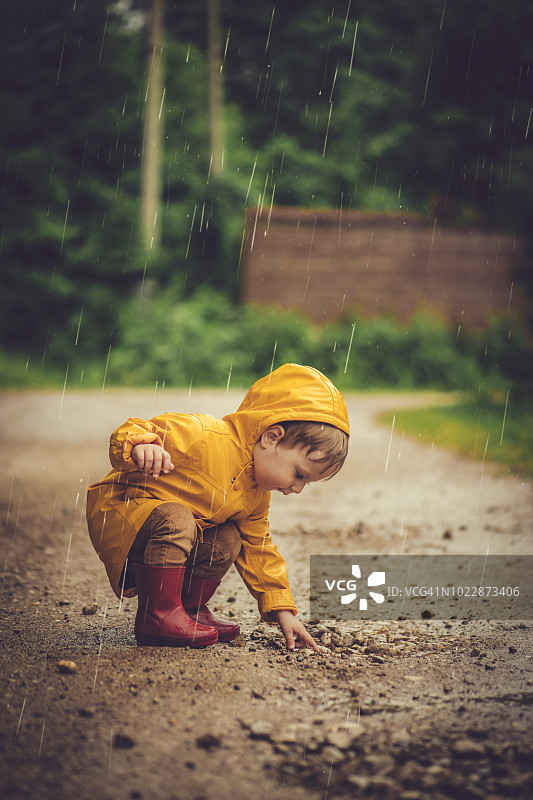 在雨中道路上玩耍的男孩图片素材