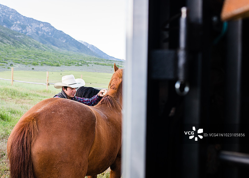 年轻的牧场主在清晨梳理他的马匹图片素材