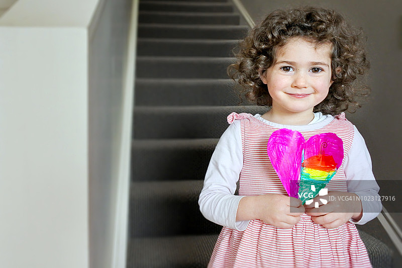 女孩拿着父亲节/母亲节心形礼品卡图片素材