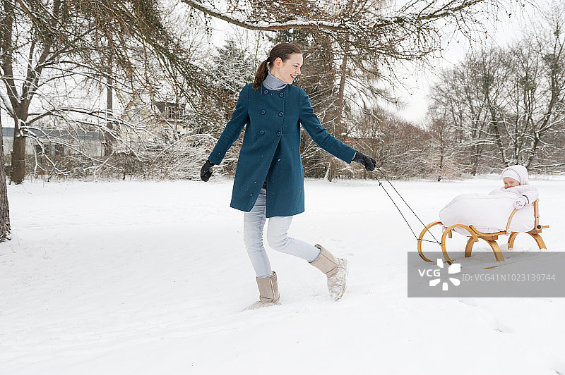 母亲拉着雪橇上的小女儿图片素材