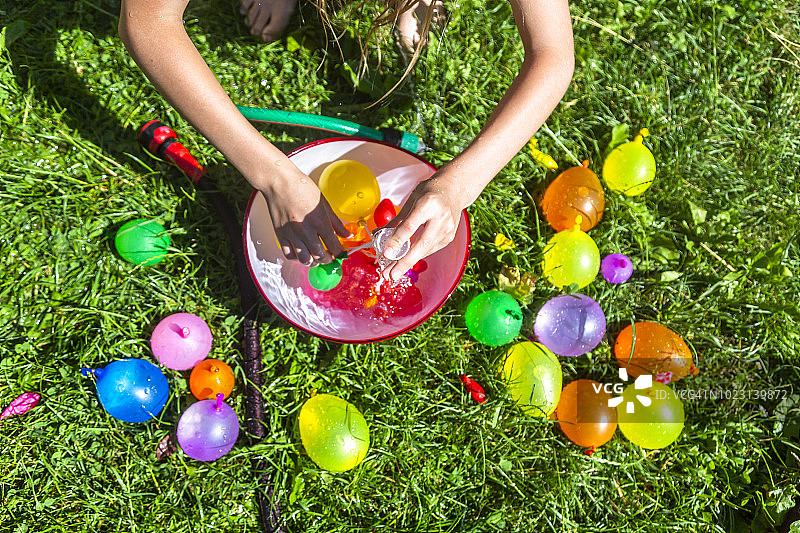 女孩在草地上准备水弹图片素材