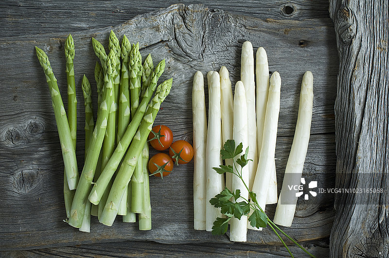 木板上的绿白芦笋、欧芹、番茄和混合胡椒图片素材