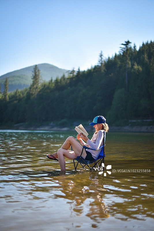 在湖边椅子上看书的女人图片素材