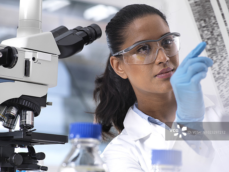 基因研究：女科学家拿着带有遗传密码的箔片图片素材