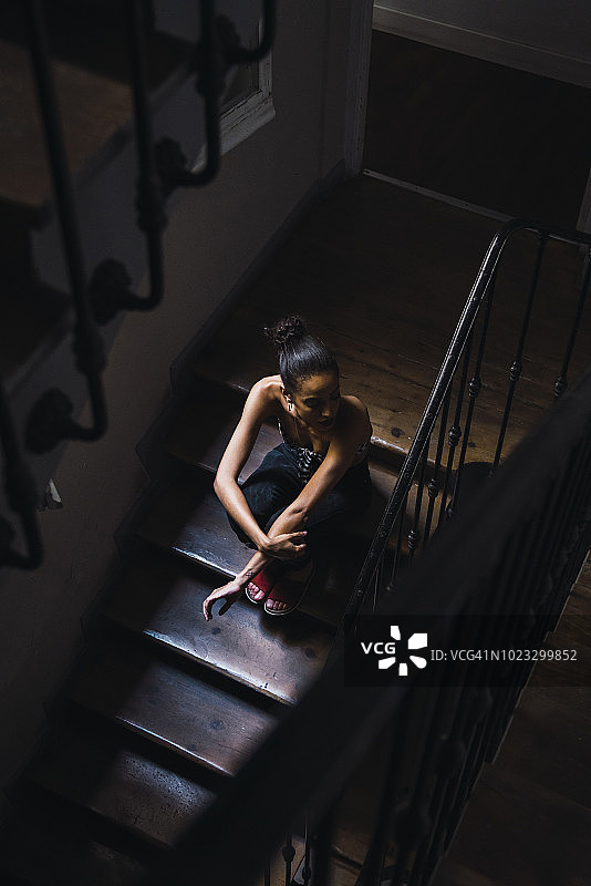 阳光下坐在楼梯上的年轻漂亮女人图片素材
