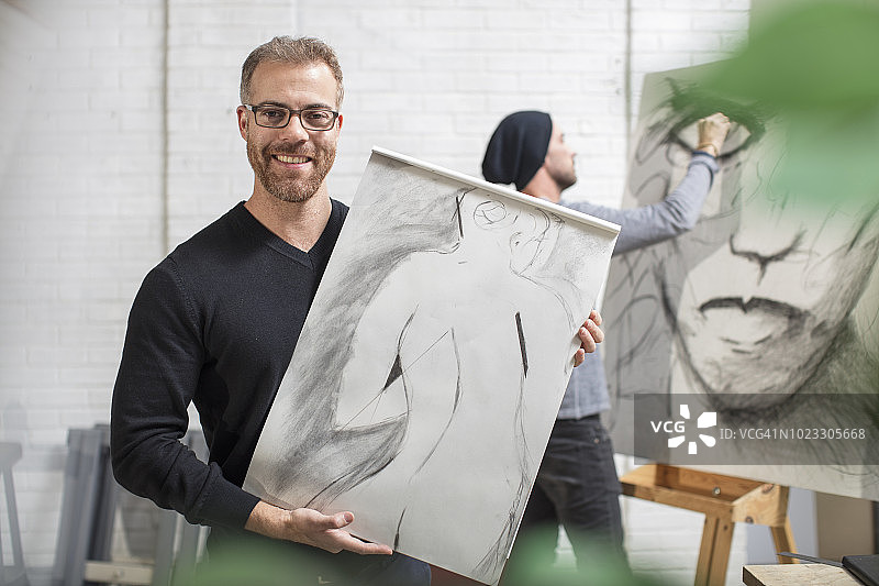 微笑的男人在艺术工作室里拿着画图片素材