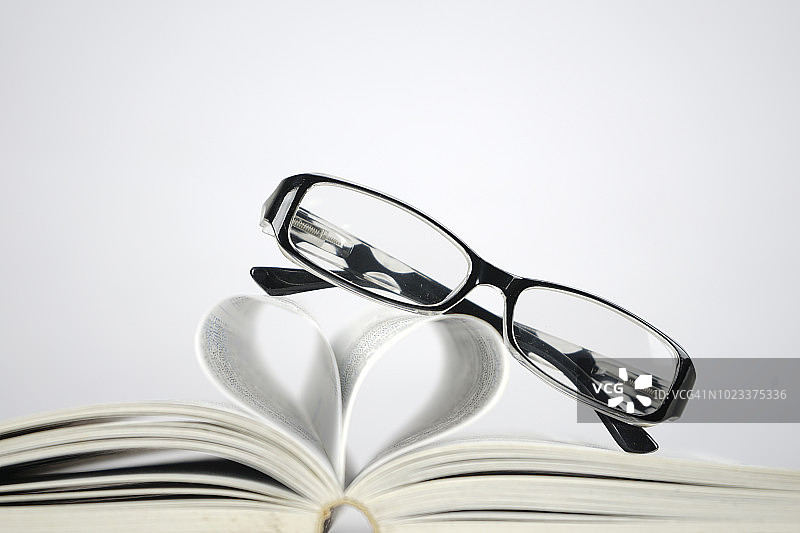 书本旁带有爱心符号的朦胧眼镜图片素材
