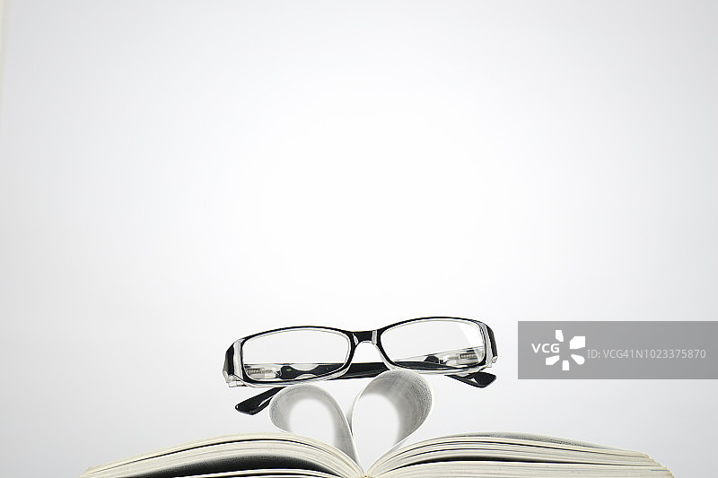 书本旁带有爱心符号的朦胧眼镜图片素材