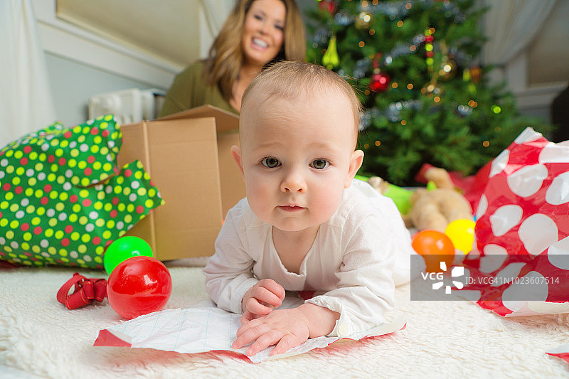 快乐的10个月大的婴儿与圣诞树和礼物图片素材