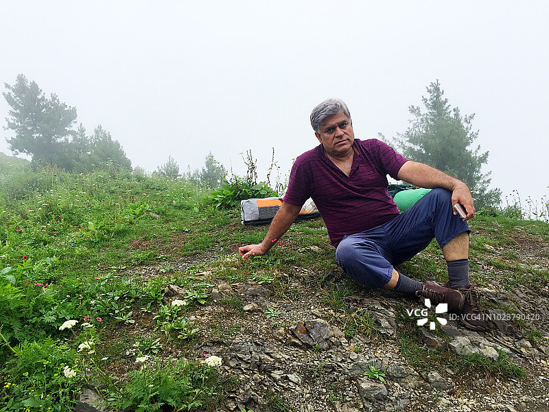 徒步者在雾蒙蒙的天气里，在茂盛的绿色小路上休息图片素材