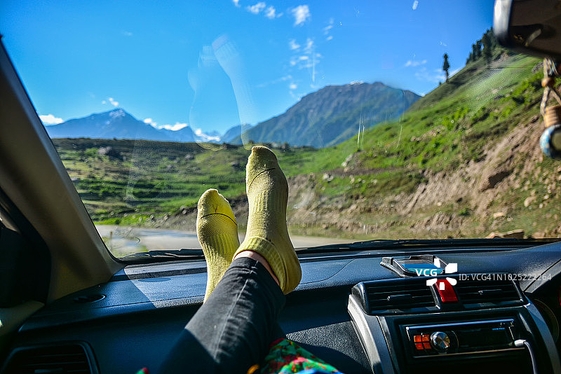女孩在山区自驾游时把脚放在仪表板上放松图片素材