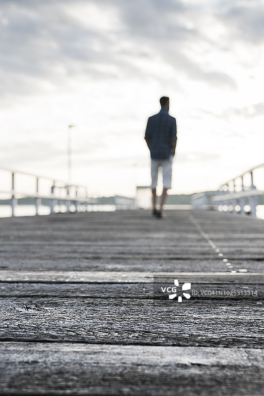 男人站在水边的木板路上图片素材