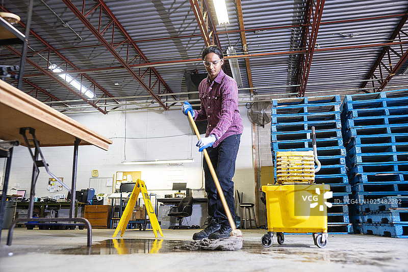 工人在仓库清理泄漏的液体图片素材