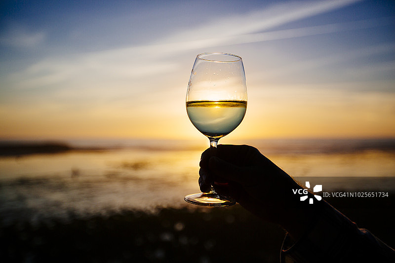 海滩日落时分，一杯白葡萄酒的剪影图片素材