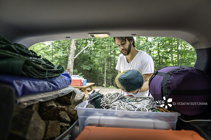 男人从后备箱卸下行李和露营物品图片素材