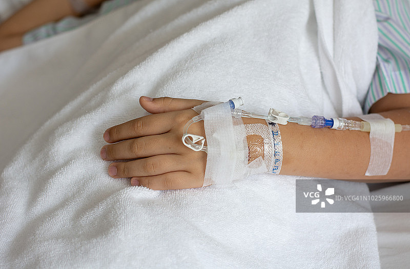 医院病房里接受静脉滴注的亚洲小男孩的手部特写图片素材