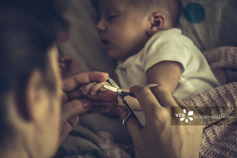 母亲给婴儿剪指甲图片素材